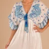 Detalle de escote en V, estampado ornamental azul y amarra con borlas