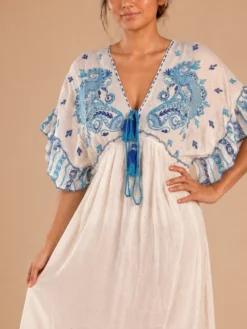 Detalle de escote en V, estampado ornamental azul y amarra con borlas